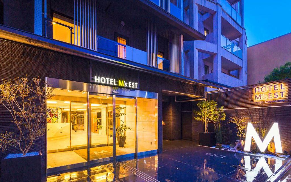 Hotel M's East entrance lit up at night with glass doors and illuminated signage