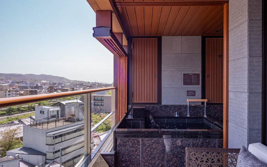 Private open-air onsen bath on a hotel balcony overlooking the Kyoto skyline